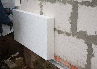 Insulation house wall outdoors. Builder installing rigid styrofoam insulation board for energy saving. Rigid extruded polystyrene insulation. - obrazy, fototapety, plakaty
