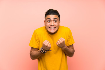 Young man with yellow shirt over isolated pink wall celebrating a victory