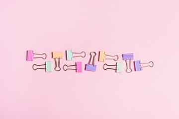 Different bright paper clip pattern on pink background.