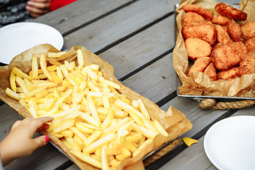 French fries and nuggets on the wooden table. A child's hand reaching for french fries.