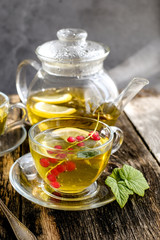  Green herbal tea with a berries in glass cup on wooden table background