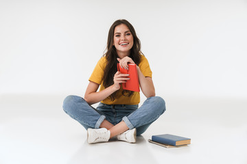 Cheery young woman isolated over white wall background writing notes in notebook.