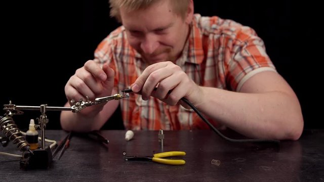 Process of replacing cable for audio rca connector.Muscled blond electrician solder wire with rosin soldering iron to RCA jack plug.