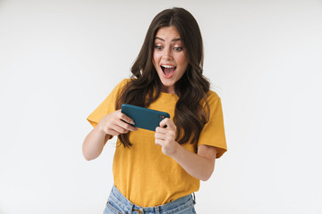 Cheery young woman posing isolated over white wall background play games by mobile phone.