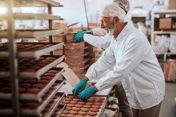 Two hardworking dedicated Caucasian employees dressed in white sterile uniforms collecting and...