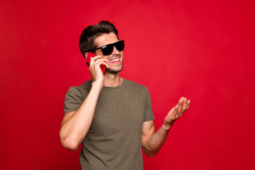 Amazing guy speaking over telephone with foreign friends wearing casual grey t-shirt isolated on red background