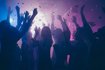 Rollo Nahaufnahme von vielen Partyleuten, die lila Lichter tanzen, Konfetti fliegen überall Nachtclub-Event-Hände erhoben tragen glänzende Kleidung © deagreez