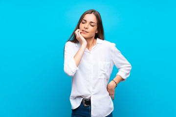 Young woman over isolated blue background with toothache