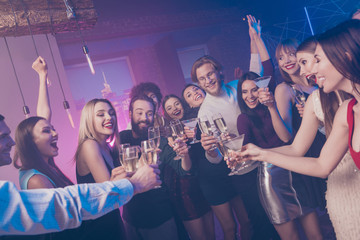 Portrait of nice adorable glamorous smart attractive cheerful cheery glad ladies and guys having fun clinking wineglasses birthday tradition surprise at fogged lights nightclub indoors