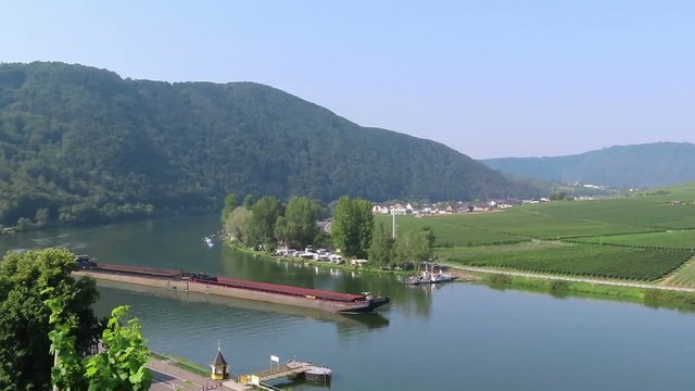 industrial ship driving along moselle river with its vineyard landscape in Germany.