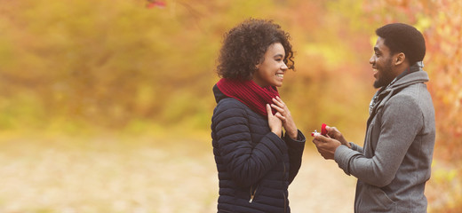 Romantic man proposing to woman in autumn park