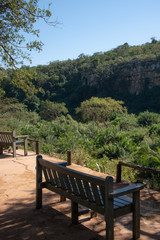 A bench overlooking the cliffs and dense vegetation along an African river.