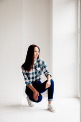Girl in plaid shirt and jeans is on white background