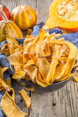 Sun-dried organic pumpkin slices, hokkaido butternut squash chips, on old rustic wooden background...