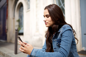 Fototapeta premium beautiful young woman looking at mobile phone in city