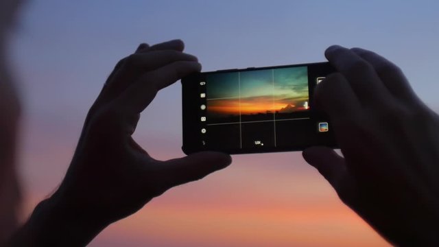Tourist taking picture of sunset sky