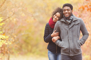 Fototapeta premium Romantic walk. Afro couple walking through autumn park