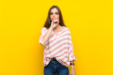 Young woman over isolated yellow background showing a sign of silence gesture putting finger in...