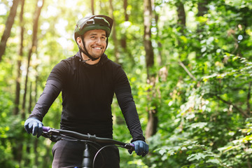 Joyful male bicyclist cycling in mountain forest