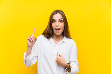 Young woman over isolated yellow background with surprise facial expression
