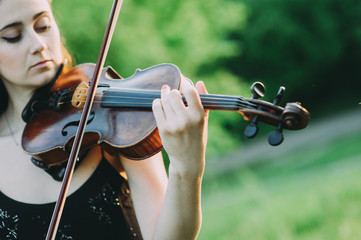 beautiful girl with long hair plays the violin in the forest