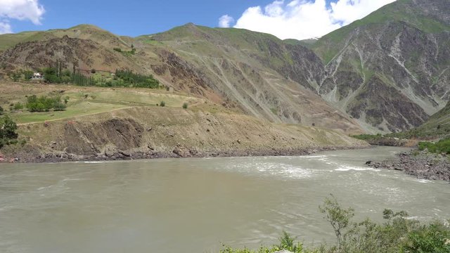 Kulob to Qalai Khumb Pamir Highway along the Panj River with View of a Village on the Afghanistan Side on a Sunny Blue Sky Day