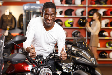 Fototapeta na wymiar Glad Afro American man posing near motorcycle
