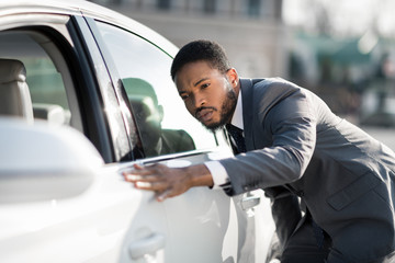 The final check. Afro man examining new car at dealership