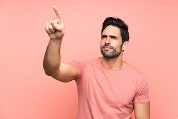Handsome young man over isolated pink background touching on transparent screen