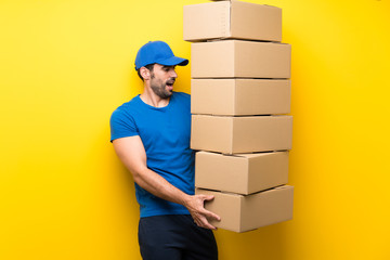 Young delivery man over isolated yellow wall