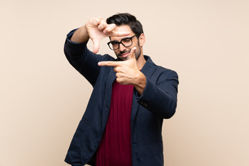 Handsome young man over isolated background focusing face. Framing symbol