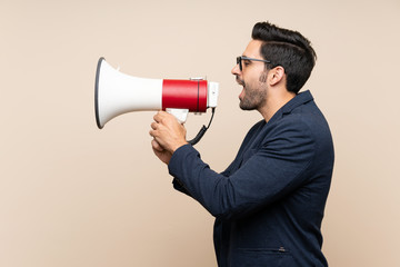 Handsome young man over isolated background shouting through a megaphone