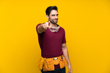 Handsome young craftsman over isolated yellow background points finger at you with a confident...