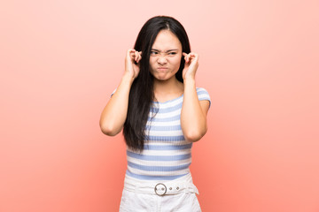 Obraz na płótnie Canvas Teenager asian girl over isolated pink background frustrated and covering ears