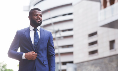 Confident black businessman in stylish suit looking aside outdoors
