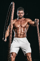 Fototapeta na wymiar Muscular Men Battling Ropes as Part of His Cross Training Regime