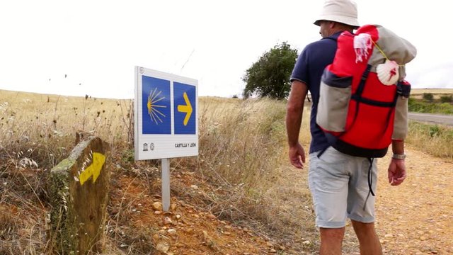 way of st james to compostela , pilgrims couple  with arrow and shell signals , video hd footage