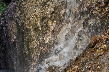 Fototapeta na wymiar Intentionally Blurred water drops splashing between rocks to a stream