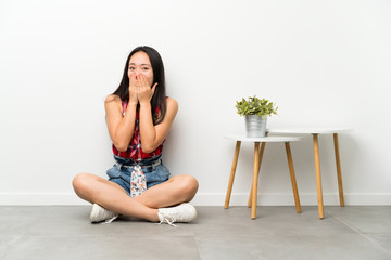 Teenager asian girl sitting on the floor with surprise facial expression