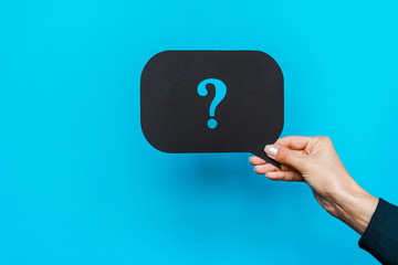 cropped view of woman holding black speech bubble with question mark on blue
