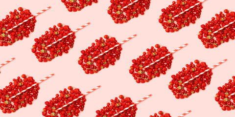Summer fruit concept pattern. Red ripe berries in the shape of a glass with fruit juice and a straw