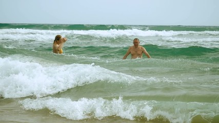 Middle-aged two women and one man dressed in swimming suits having fun on the Mediterranean coast, enjoying them travel, holiday and sea. Greece. 4K