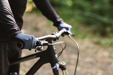 Sportsman holding bike handle on woods background
