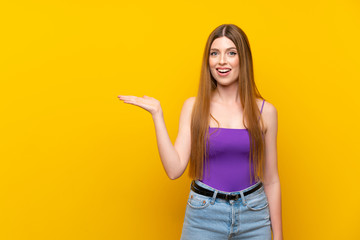 Young woman over isolated yellow background holding copyspace imaginary on the palm to insert an ad