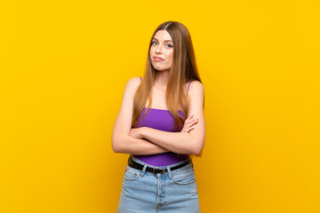 Young woman over isolated yellow background making doubts gesture while lifting the shoulders