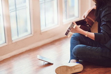 Cropped shot photo of woman training guitar with using smart phone mobile.