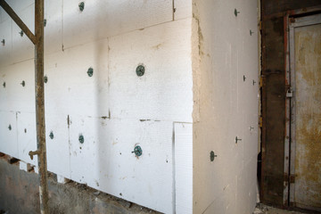 Insulation work of house walls with styrofoam sheets.
