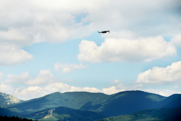 Fototapeta na wymiar Quadrocopter in flight over the green mountains.