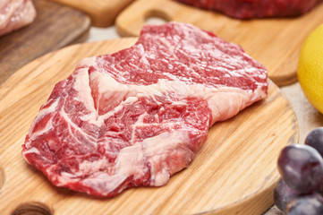 Close up view of raw meat on light wooden cutting board