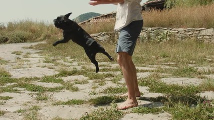 Man plays with french bulldog outside in park